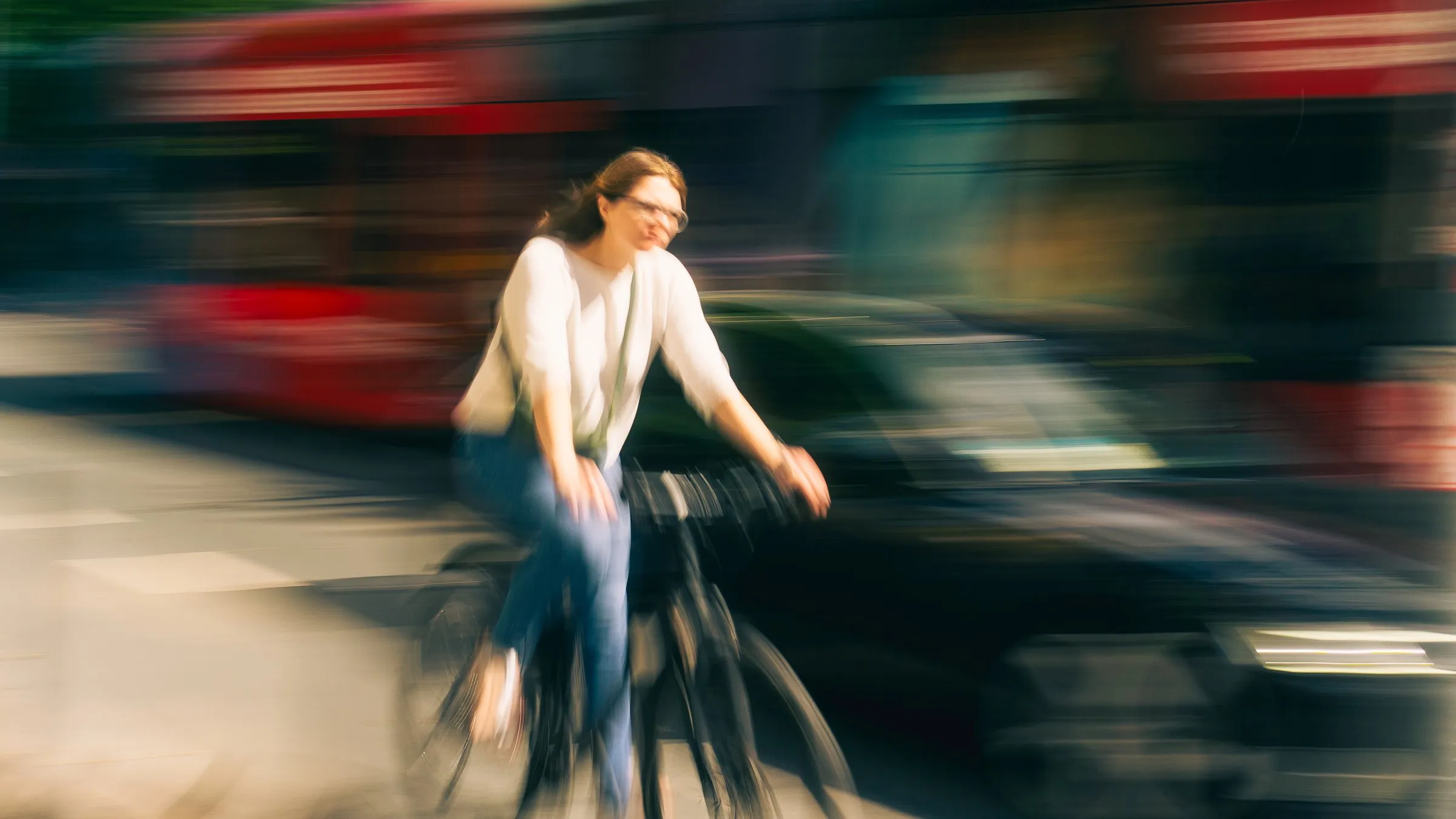 A man stands still in the middle of the frame while the people and traffic around him blur past.